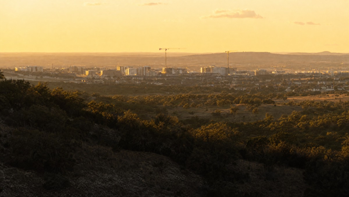 Central Texas hill country at golden hour with construction cranes on the horizon